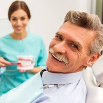 An older man smiling with a dentist