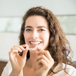 woman holding clear braces aligner