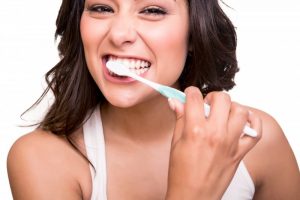 woman smiling brushing her teeth