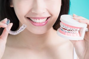 Woman holding clear aligners and braces